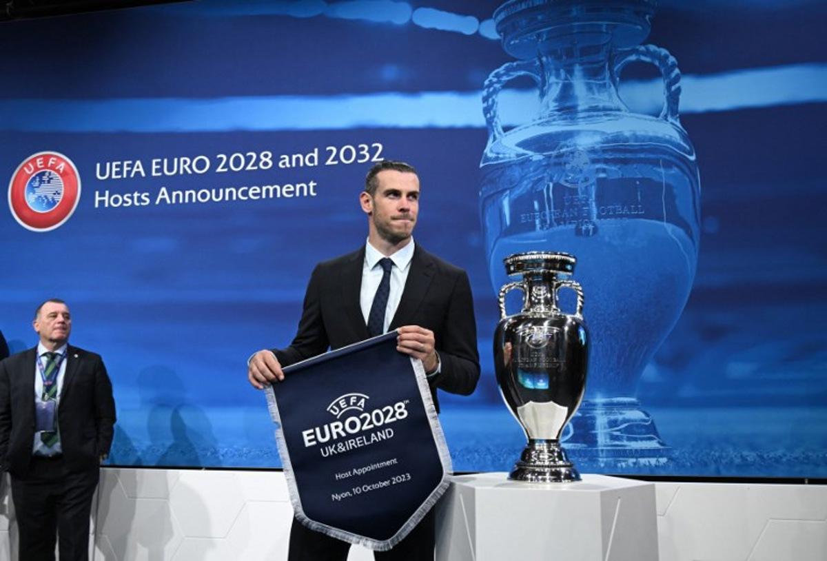 Welsh retired professional footballer, heading the delegation of UK and Ireland Gareth Bale holds the pennant as he poses after United Kingdom and Ireland were elected to host the Euro 2028 fooball tournament during a ceremony at the UEFA headquarters  in Nyon on October 10, 2023. Seven years after awarding Euro-2024 to Germany, UEFA announced on October 10, 2023 the hosts for the next two editions: The United Kingdom and Ireland are due to host the tournament together in 2028, followed by the unprecedented tandem of Italy and Turkey in 2032.  Fabrice COFFRINI / AFP