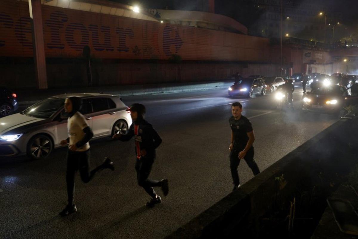 Paris Saint-Germain (PSG) supporters run after police used tear gas to disperse them after a group of supporters blocked the highway near the Parc des Princes Stadium in Paris on May 7, 2025, while they celebrated their team's victory in the UEFA Champions League semi-final second leg football match against Arsenal.  GEOFFROY VAN DER HASSELT / AFP