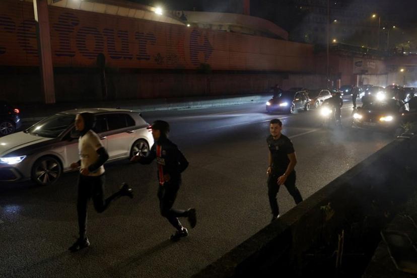 Paris Saint-Germain (PSG) supporters run after police used tear gas to disperse them after a group of supporters blocked the highway near the Parc des Princes Stadium in Paris on May 7, 2025, while they celebrated their team's victory in the UEFA Champions League semi-final second leg football match against Arsenal.  GEOFFROY VAN DER HASSELT / AFP