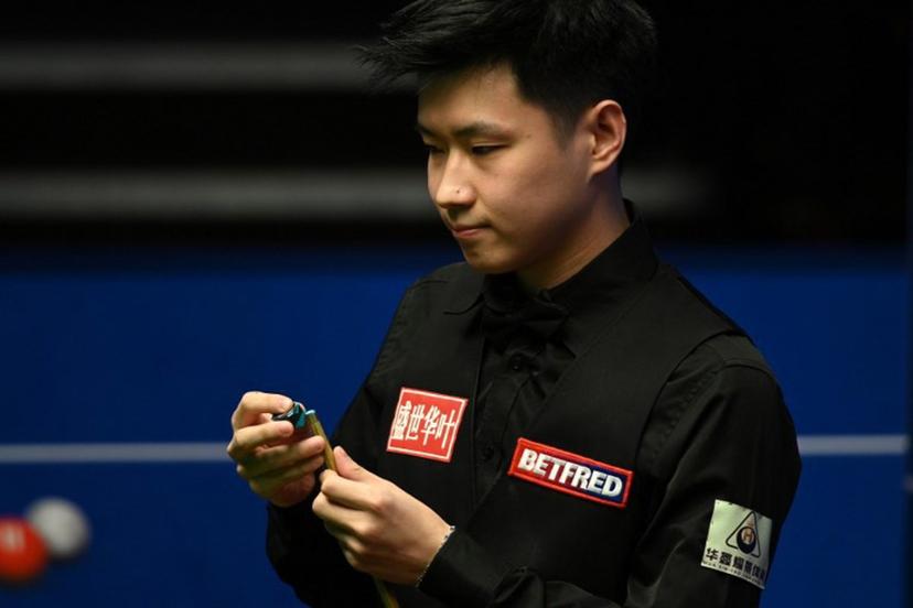 China's Zhao Xintong chalks his cue while playing against Scotland's Stephen Maguire during their World Championship Snooker second round match at The Crucible in Sheffield, England on April 22, 2022.   Oli SCARFF / AFP