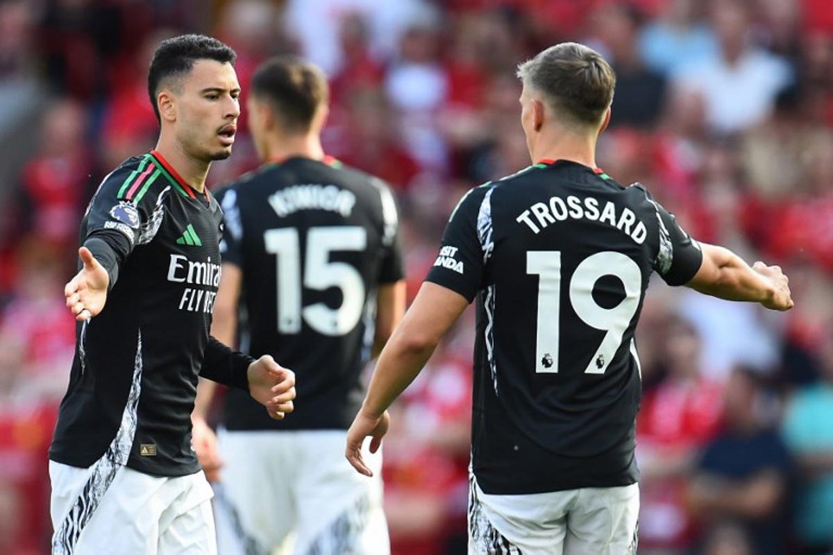 Arsenal's Brazilian midfielder #11 Gabriel Martinelli (L) celebrates with Arsenal's Belgian midfielder #19 Leandro Trossard (R) after scoring their first goal during the English Premier League football match between Liverpool and Arsenal at Anfield in Liverpool, north west England on May 11, 2025.  PETER POWELL / AFP