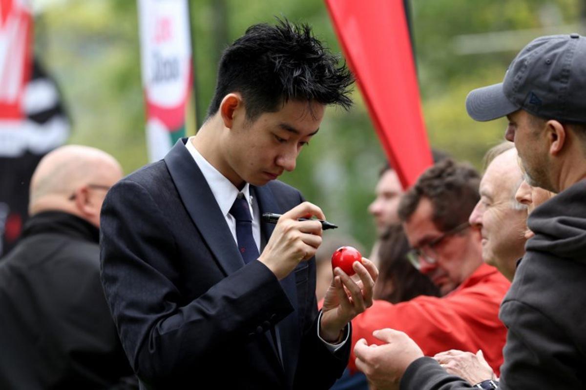 Chinese snooker player Wu Yize signs a snooker ball during a media day launching the start of the World Snooker Championship 2026 at Crucible Theatre in Sheffield, northern England, on April 17, 2026.  Darren Staples / AFP
