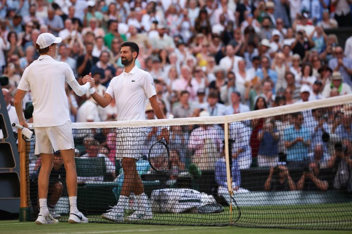 Italy's Jannik Sinner (L) shakes hands with Serbia's Novak Djokovic after winning their men's singles semi-final tennis match on the twelfth day of the 2025 Wimbledon Championships at The All England Lawn Tennis and Croquet Club in Wimbledon, southwest London, on July 11, 2025.  HENRY NICHOLLS / AFP