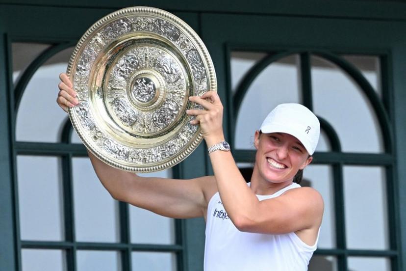 Poland's Iga Swiatek celebrates with the winner's trophy, the Venus Rosewater Dish, as she shows it to the crowd from the Centre Court balcony after winning her women's singles final tennis match against US player Amanda Anisimova on the thirteenth day of the 2025 Wimbledon Championships at The All England Lawn Tennis and Croquet Club in Wimbledon, southwest London, on July 12, 2025.  Kirill KUDRYAVTSEV / AFP