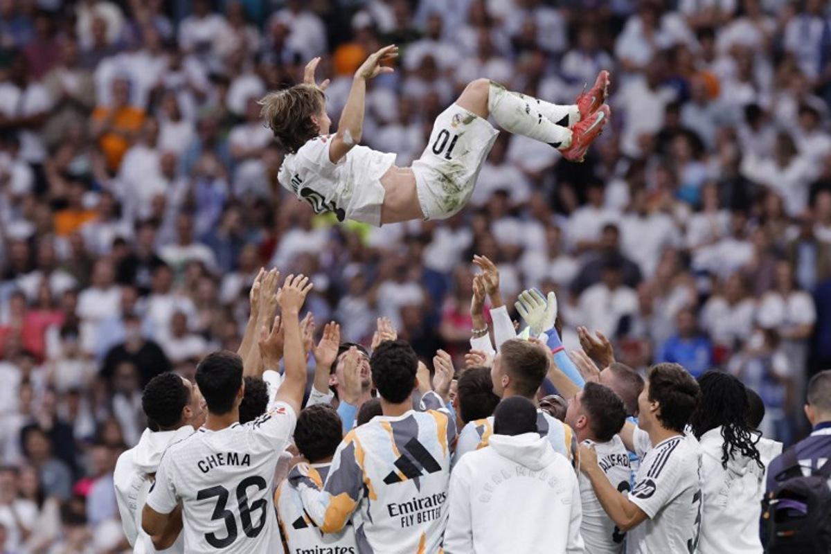 Real Madrid's Croatian midfielder #10 Luka Modric is tossed into the air by teammates at the end of the Spanish league football match between Real Madrid CF and Real Sociedad at Santiago Bernabeu Stadium in Madrid on May 24, 2025.  OSCAR DEL POZO / AFP