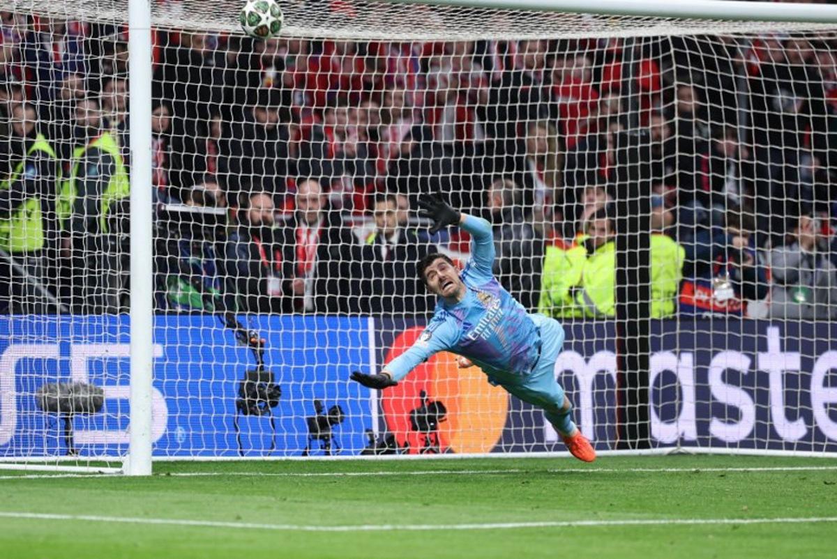 Real Madrid's Belgian goalkeeper #01 Thibaut Courtois dives for the ball during the penalty shoot out after the UEFA Champions League Round of 16 second leg football match between Club Atletico de Madrid and Real Madrid CF at the Metropolitano stadium in Madrid on March 12, 2025.  Thomas COEX / AFP