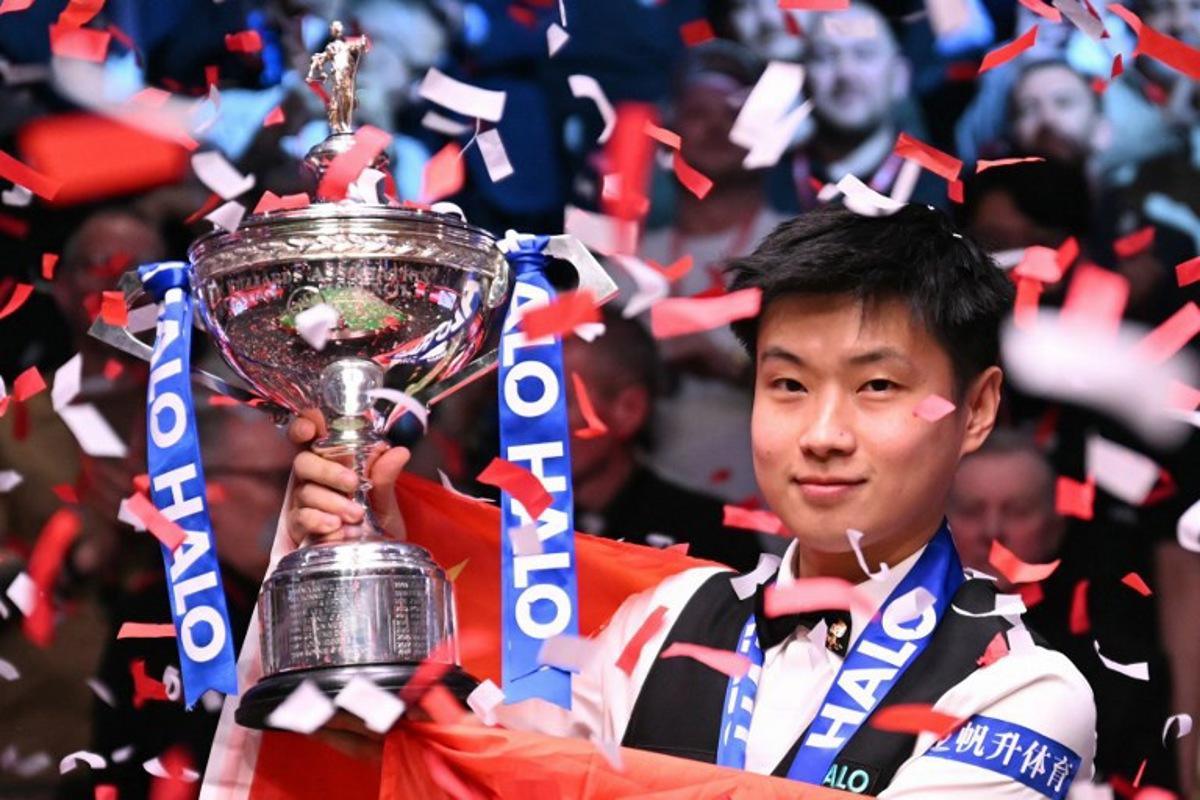 China's Zhao Xintong poses with the trophy after victory over Wales' Mark Williams in the World Championship Snooker final at The Crucible in Sheffield, northern England on May 5, 2025.  Zhao Xintong became the first Chinese player to win the World Snooker Championship as the qualifier completed his stunning march to the title with a 18-12 victory against Mark Williams in the final on Monday. Oli SCARFF / AFP