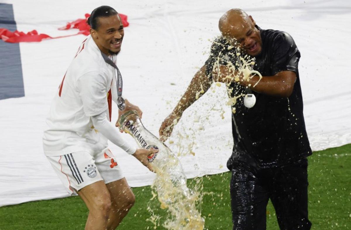 Bayern Munich's Belgian head coach Vincent Kompany is doused with beer by Bayern Munich's German forward #10 Leroy Sane (L) after the German first division Bundesliga football match between Bayern Munich and Borussia Moenchengladbach in Munich on May 10, 2025.  Michaela STACHE / AFP