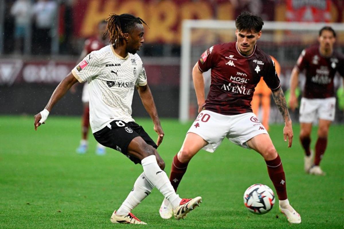 Reims' French midfielder #06 Valentin Atangana (L) and Metz's French midfielder #20 Jessy Deminguet (R) fight for the ball during the French L1 - L2 playoff first leg football match between FC Metz and Stade de Reims at the Saint-Symphorien Stadium in Metz, northeastern France, on May 21, 2025.  Jean-Christophe VERHAEGEN / AFP