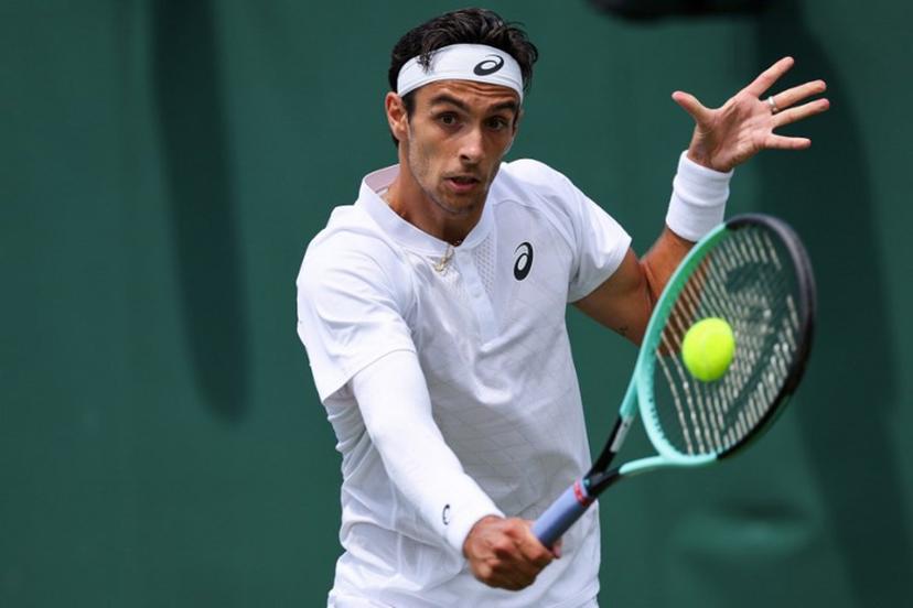 Italy's Lorenzo Musetti plays a backhand return to Georgia's Nikoloz Basilashvili during their men's singles first round tennis match on the second day of the 2025 Wimbledon Championships at The All England Lawn Tennis and Croquet Club in Wimbledon, southwest London, on July 1, 2025.  Adrian Dennis / AFP