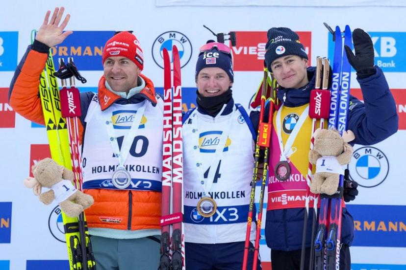 (From left) Second place Germany's Philipp Nawrath, winner Norway's Johan-Olav Botn and third place France's Eric Perrot celebrate on the podium after the men's 15km mass start event of the IBU Biathlon World Cup in Holmenkollen, Oslo on March 22, 2026.  Heiko Junge / NTB / AFP