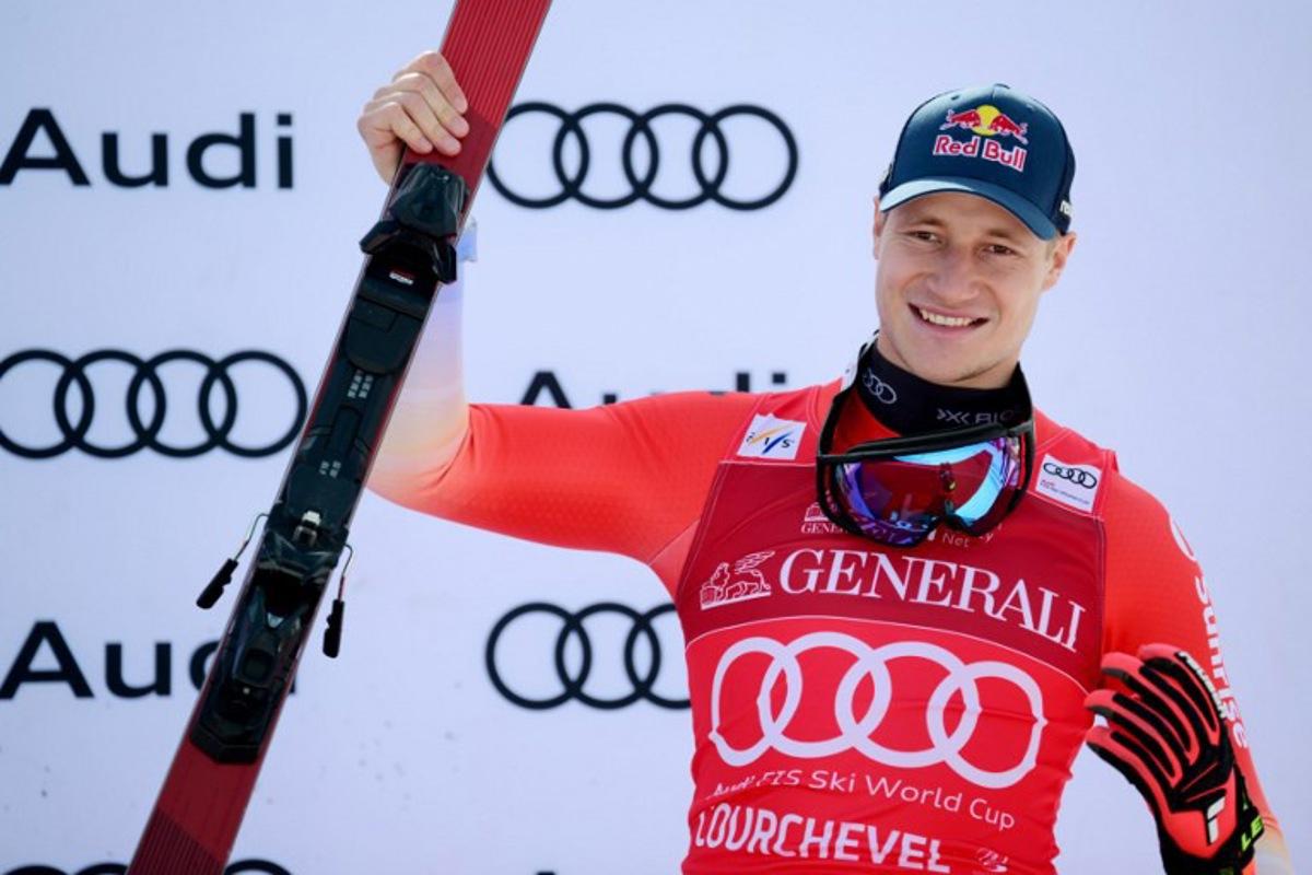 Third placed Switzerland's Marco Odermatt celebrates on the podium after the Men's Downhill event of the FIS Alpine World Cup in Courchevel, French Alps, on March 13, 2026.  Olivier CHASSIGNOLE / AFP