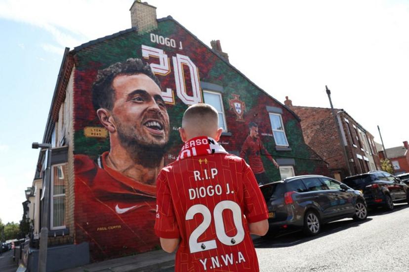 A fan stands in front of a mural by artist Paul Curtis, of Liverpool's late Portuguese striker Diogo Jota and his brother Andre Silva before the first of two pre season friendly football matches between Liverpool and Athletic Bilbao, near Anfield in Liverpool, north west England on August 4, 2025.  Darren Staples / AFP