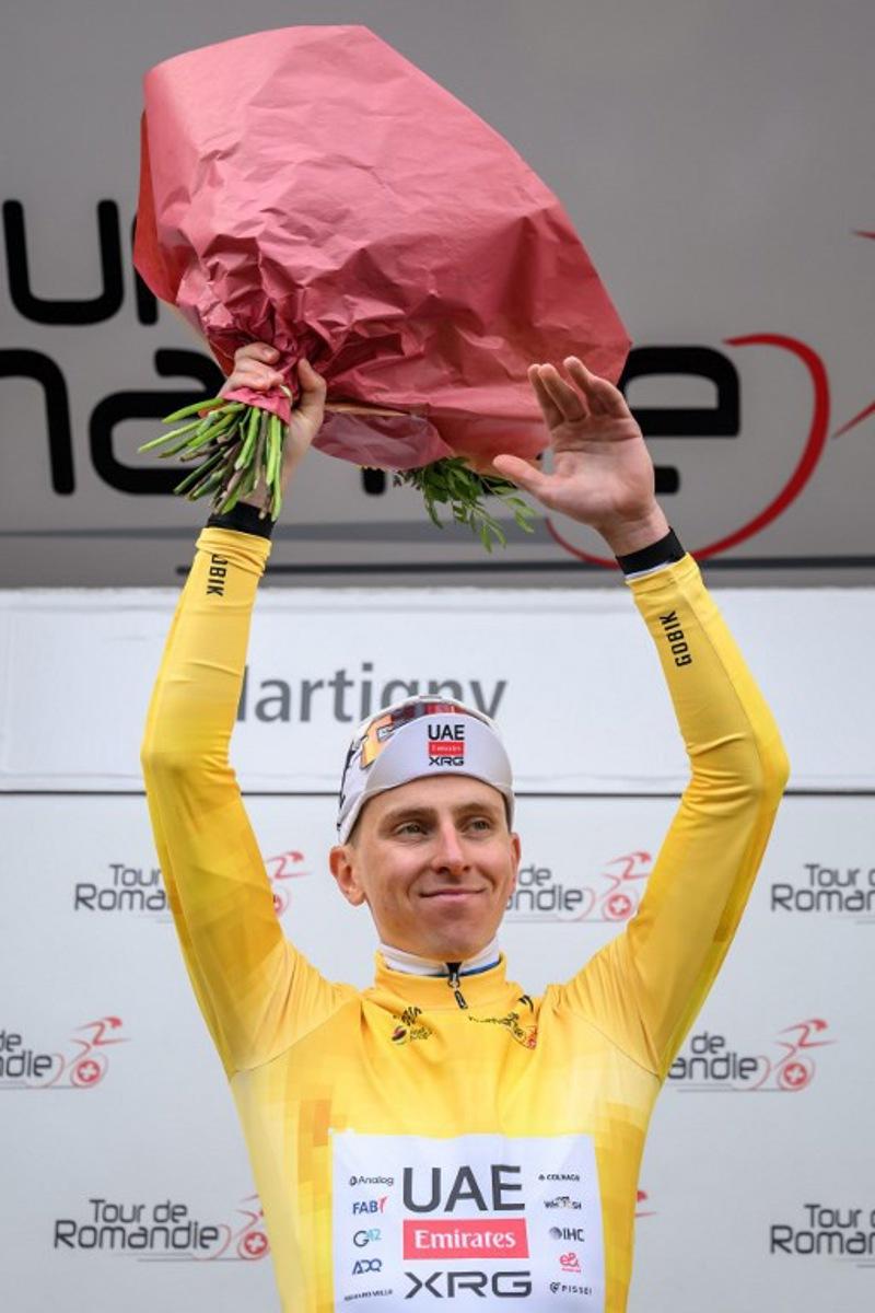 UAE Team Emirates-XRG's Slovenian rider Tadej Pogacar wearing the overall leader's yellow jersey celebrates on the podium of the first stage of the Tour of Romandie UCI cycling World tour, a 171.2 km loop from Martigny-Ville to Martigny-Ville, in Martigny, on April 29, 2026.  Fabrice COFFRINI / AFP