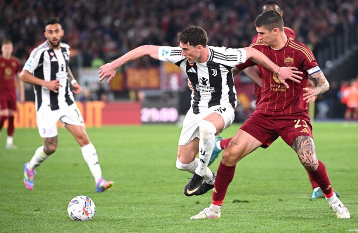 Juventus' Serbian forward #9 Dusan Vlahovic (C) fights for the ball with Roma's Italian defender #23 Gianluca Mancini (R) during the Italian Serie A football match AS Roma vs Juventus at Olympic stadium in Rome on April 6, 2025.  Alberto PIZZOLI / AFP