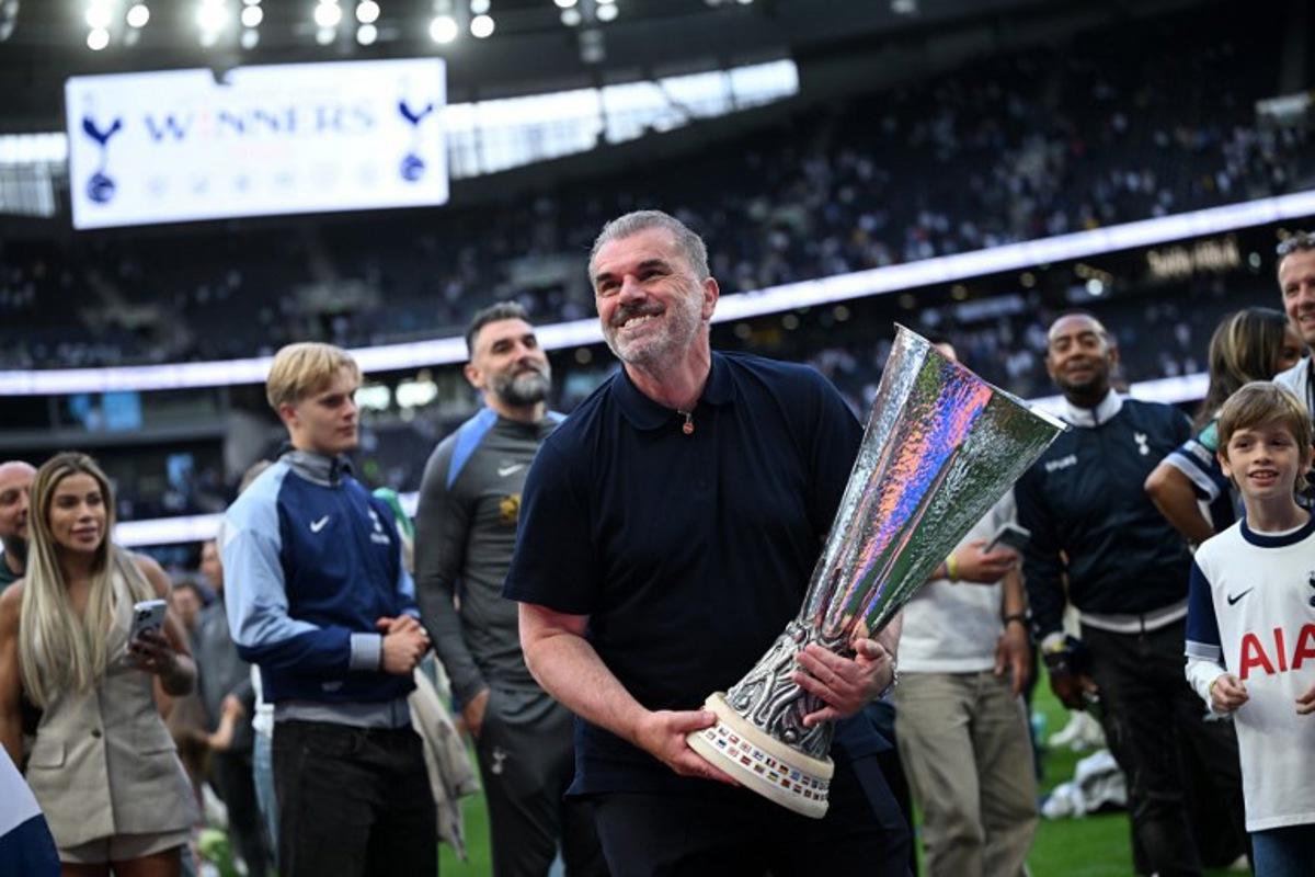 Tottenham Hotspur's Greek-Australian Head Coach Ange Postecoglou holds aloft the Europa League trophy, following their mid-week win in the Europa League Final on May 21, as he and the team display it for fans following the English Premier League football match between Tottenham Hotspur and Brighton and Hove Albion at the Tottenham Hotspur Stadium in London, on May 25, 2025.  JUSTIN TALLIS / AFP