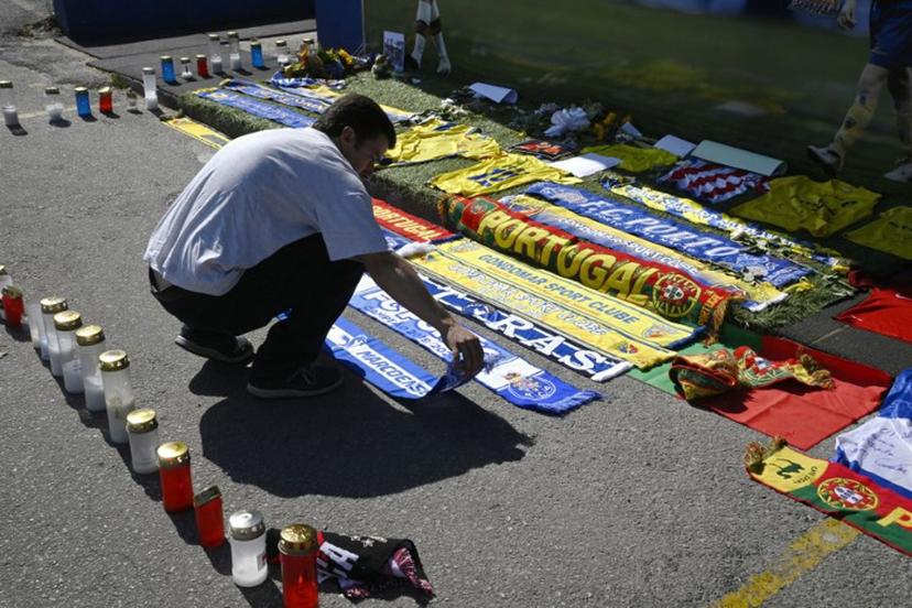 A well-wisher leaves a scarf at a memorial for Liverpool's Portuguese forward Diogo Jota, set up at the Gondomar Sport Clube's stadium, where the late footballer began his career, in Gondomar, on the outskirts of Porto, on July 4, 2025. Liverpool forward Diogo Jota and his brother died in a car crash in Spain yesterday, sparking widespread grief just after the Portugal star had got married. Their funeral will take place tomorrow in Gondomar, on the outskirts of Porto, at 10:00 a.m. local time (0900 GMT). MIGUEL RIOPA / AFP
