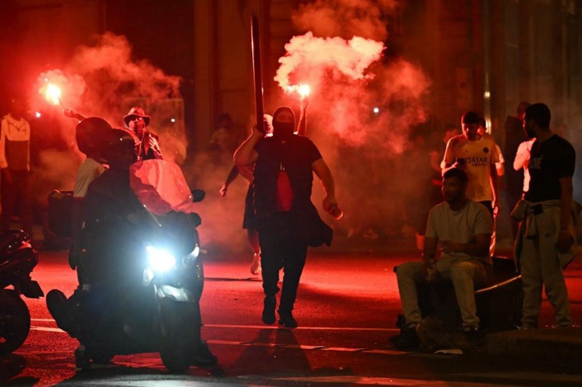 Paris Saint-Germain (PSG) supporters gather holding flares on a street in Paris early June 1, 2025, during celebrations following their 5-0 victory in the UEFA Champions League final football match between Paris Saint-Germain (PSG) and Inter Milan held in Munich.  LOU BENOIST / AFP