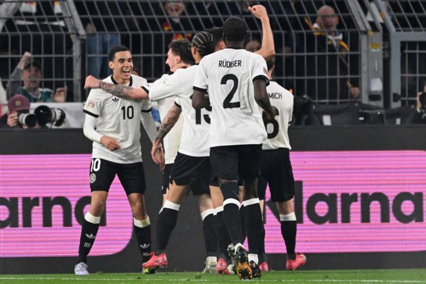 Germany's midfielder #10 Jamal Musiala (L) celebrates scoring the 2-0 goal with his teammates during the UEFA Nations League quarter-final second leg football match Germany v Italy at the Signal Iduna Park stadium in Dortmund, western Germany on March 23, 2025.   Kirill KUDRYAVTSEV / AFP