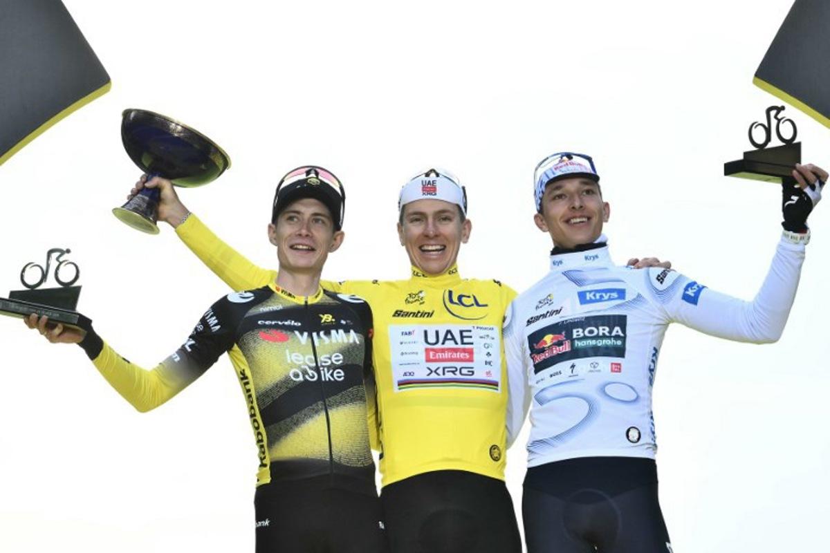 Overall winner UAE Team Emirates - XRG team's Slovenian rider Tadej Pogacar (C) wearing the overall leader's yellow jersey, second-placed Team Visma - Lease a bike team's Danish rider Jonas Vingegaard (L), and third-placed Red Bull - BORA - hansgrohe team's German rider Florian Lipowitz (R) celebrate on the podium after the 21st and final stage of the 112th edition of the Tour de France cycling race, 132.3 km between Mantes-la-Ville and Paris Champs-Élysees, on July 27, 2025.  Marco BERTORELLO / AFP