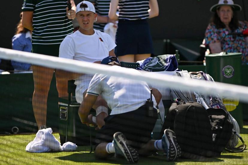Denmark's Holger Rune receives medical treatment as he plays against Chile's Nicolas Jarry during their men's singles first round tennis match on the first day of the 2025 Wimbledon Championships at The All England Lawn Tennis and Croquet Club in Wimbledon, southwest London, on June 30, 2025.  Glyn KIRK / AFP