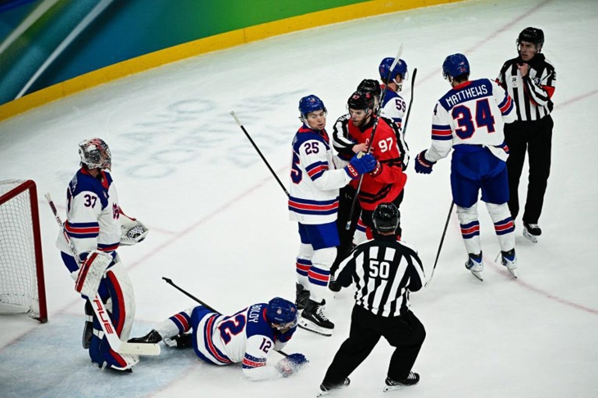 USA's #12 Matt Boldy (down) reacts after a scuffle with Canada's #97 Connor McDavid (4th R)  during the men's gold medal ice hockey match between Canada and USA at the Milano Santagiulia Ice Hockey Arena during the Milano Cortina 2026 Winter Olympic Games in Milan, on February 22, 2026.  JULIEN DE ROSA / AFP