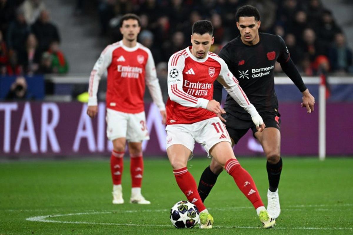 Bayer Leverkusen's French forward #11 Martin Terrier (C) and Bayer Leverkusen's English defender #04 Jarell Quansah (R) vie for the ball during the UEFA Champions League, Last 16, first-leg football match Bayer 04 Leverkusen vs Arsenal in Leverkusen, western Germany, on March 11, 2026.    UWE KRAFT / AFP