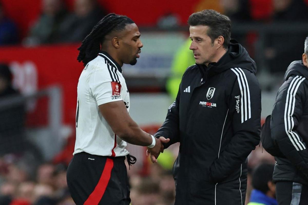 Fulham's Spanish midfielder #11 Adama Traore (L) shakes hands with Fulham's Portuguese head coach Marco Silva (R) as he leaves the game, injured during the English FA Cup fifth round football match between Manchester United and Fulham at Old Trafford in Manchester, north west England, on March 2, 2025.   Darren Staples / AFP