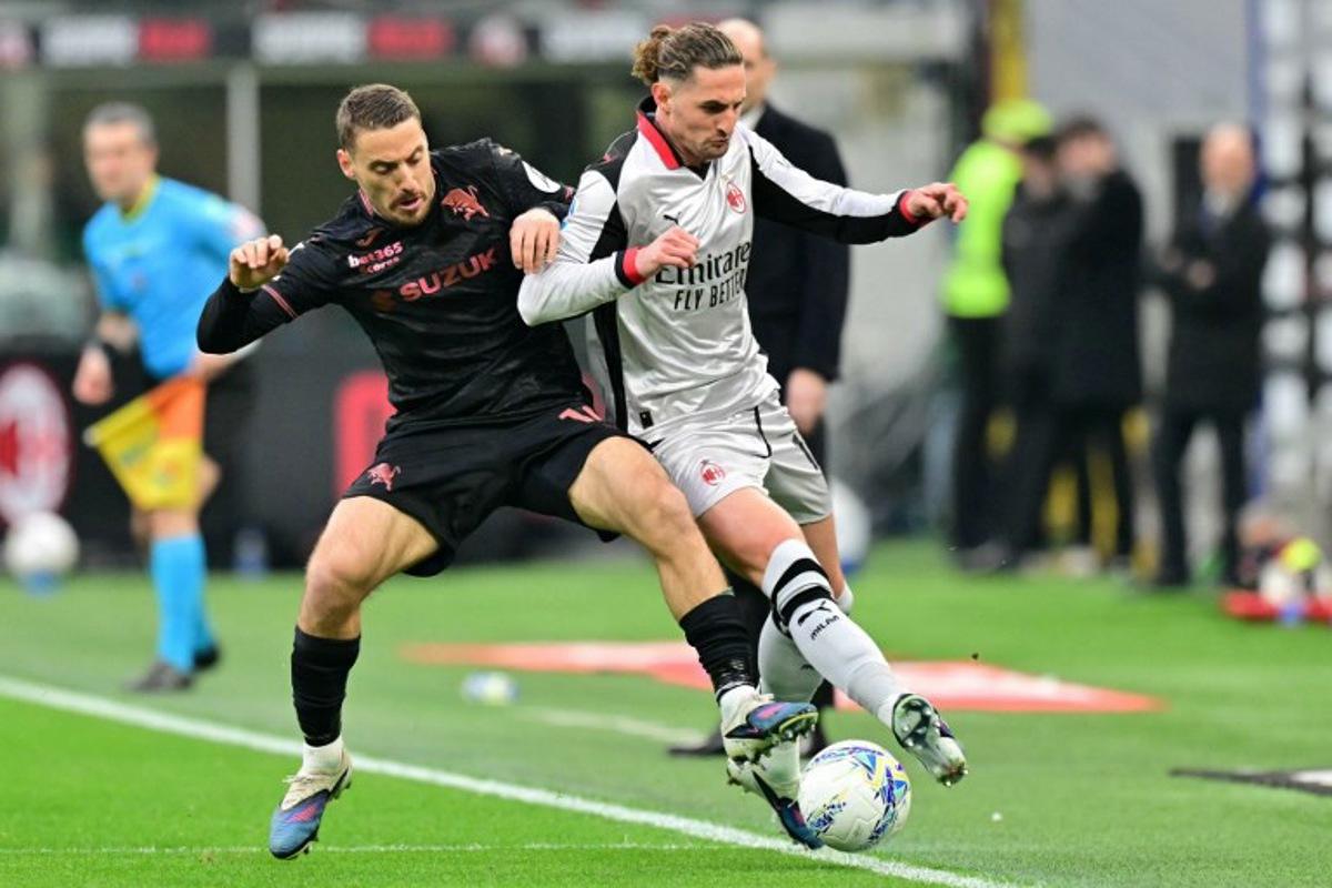 Torino's Croatian midfielder #10 Nikola Vlasic fights for the ball with AC Milan's French midfielder  #12 Adrien Rabiot (R) during the Italian Serie A football match between AC Milan and Torino at San Siro stadium in Milan, northern Italy, on March 21, 2026.  Stefano RELLANDINI / AFP