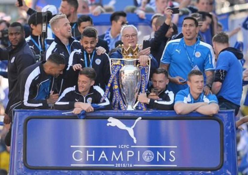 (L-R) Leicester City's English defender Wes Morgan, Leicester City's Danish goalkeeper Kasper Schmeichel, Leicester City's Algerian midfielder Riyad Mahrez, Leicester City's Italian manager Claudio Ranieri, Leicester City's English midfielder Danny Drinkwater, Leicester City's Argentinian striker Leonardo Ulloa and Leicester City's German defender Robert Huth stand with the Premier league trophy as the Leicester City team take part in an open-top bus parade through Leicester to celebrate winning the Premier League title on May 16, 2016.   / AFP PHOTO / GLYN KIRK