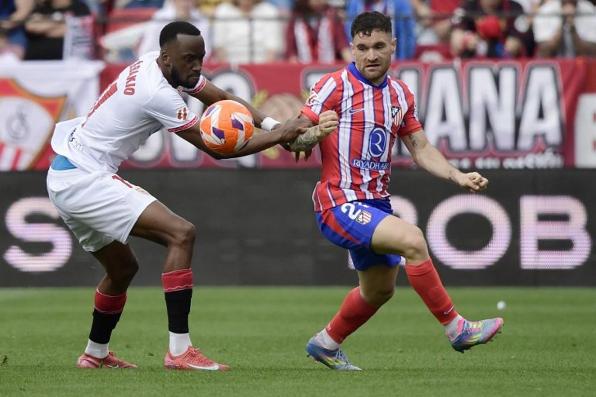 Sevilla's Belgian forward #11 Dodi Lukebakio (L) and Atletico Madrid's Spanish defender #21 Javi Galan fight for the ball during the Spanish league football match between Sevilla FC and Club Atletico de Madrid at the Ramon Sanchez Pizjuan stadium in Seville on April 6, 2025.  CRISTINA QUICLER / AFP