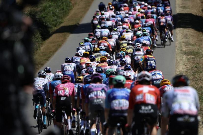 The pack of riders (peloton) cycles during the 8th stage of the 112th edition of the Tour de France cycling race, 171.4 km between Saint-Meen-le-Grand and Laval Espace Mayenne, western France, on July 12, 2025.  Anne-Christine POUJOULAT / AFP