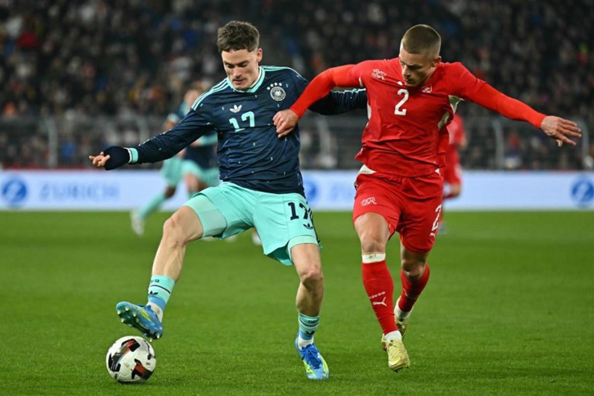 Germany's midfielder #17 Florian Wirtz fights for the ball with Switzerland's defender #2 Miro Muheim during the international friendly football match between Switzerland and Germany at St. Jakob-Park in Basel, Switzerland on March 27, 2026.  Fabrice COFFRINI / AFP