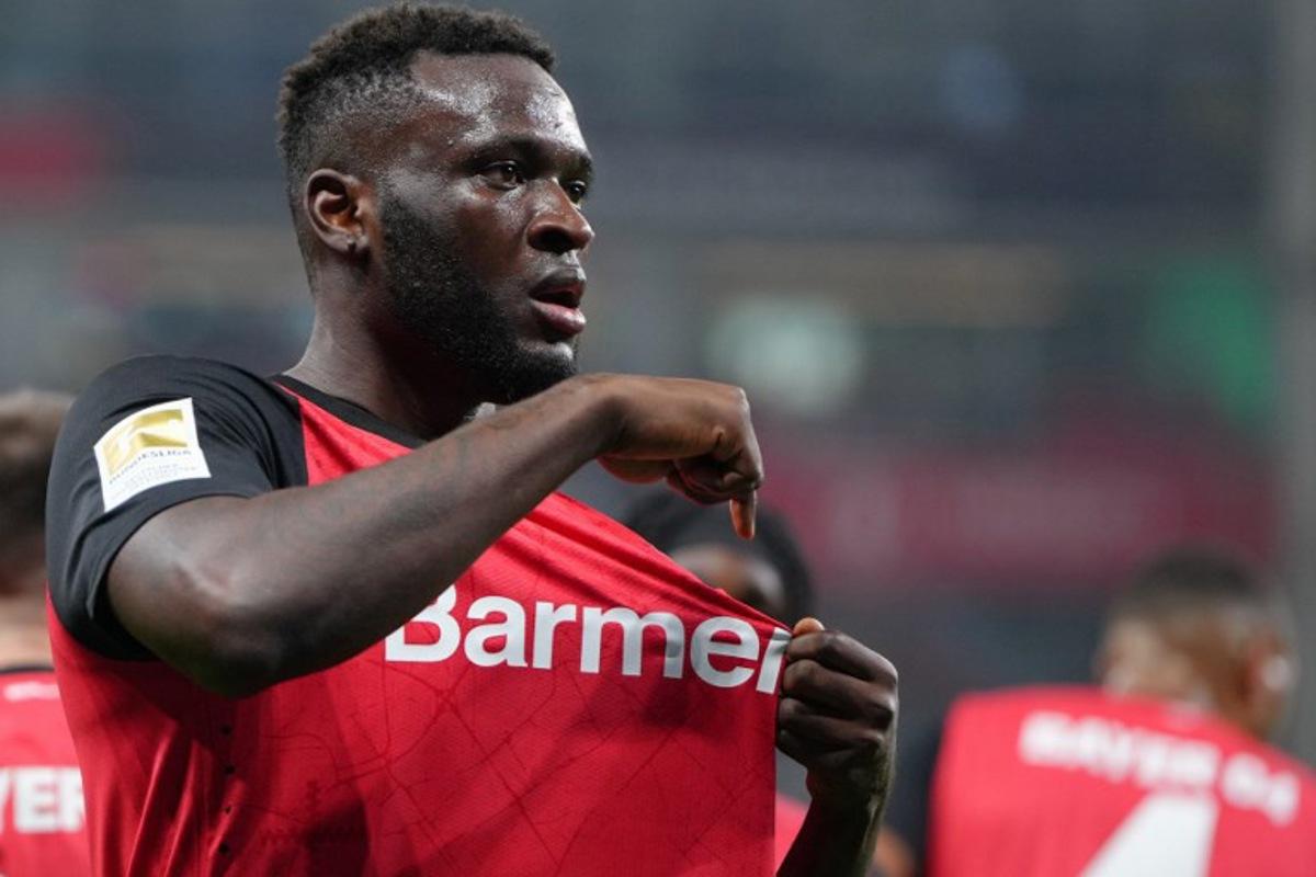 Bayer Leverkusen's Nigerian forward #22 Victor Boniface points to the club badge as he celebrates scoring the 2-1 goal with his teammates during the German first division Bundesliga football match between Bayer 04 Leverkusen and VfL Bochum in Leverkusen, western Germany on March 28, 2025.  Pau BARRENA / AFP