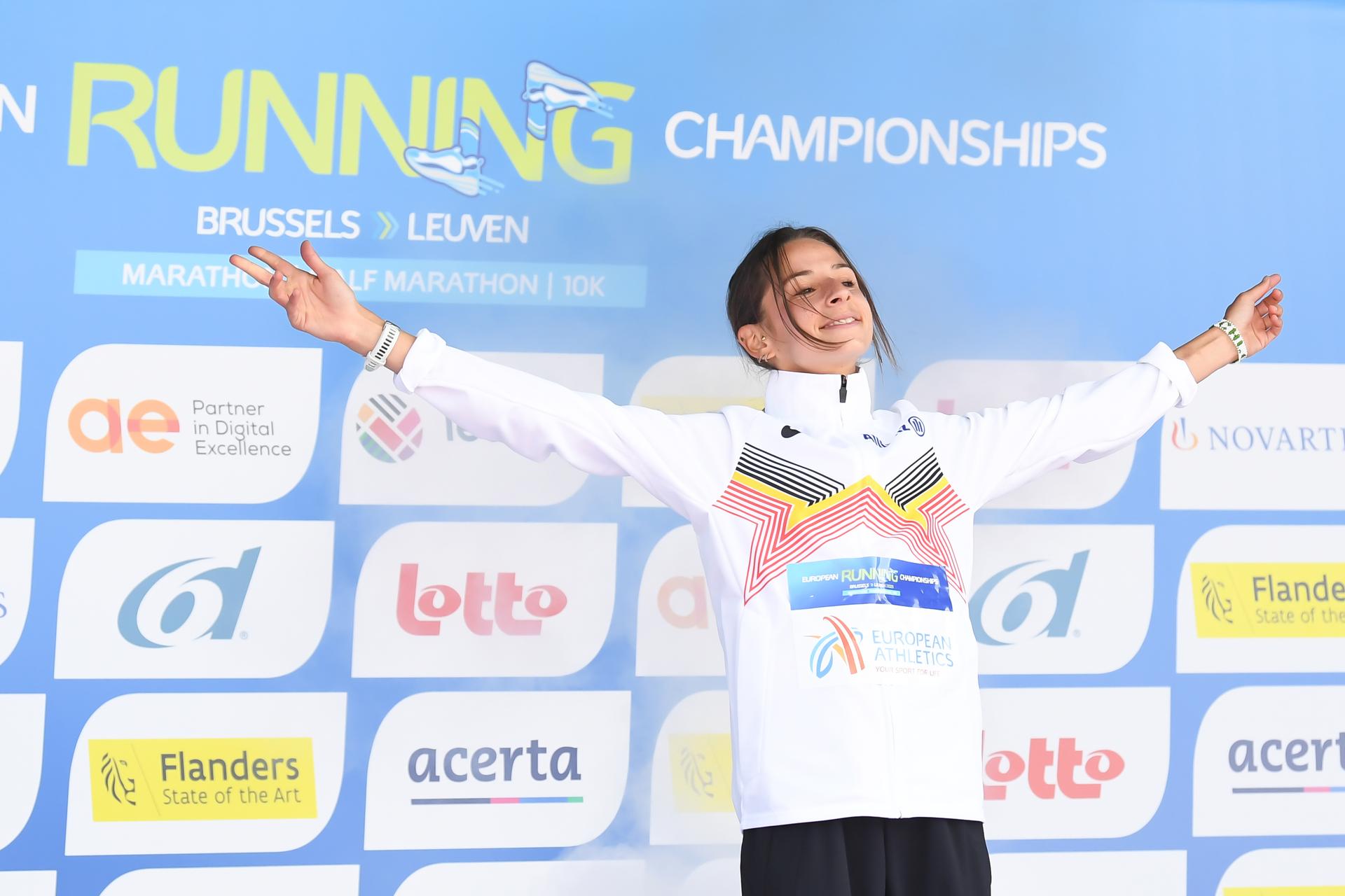 Belgian Chloe Herbiet celebrates on the podium after winning the half marathon race at European Running Championships, in Leuven, Saturday 12 April 2025. BELGA PHOTO JILL DELSAUX