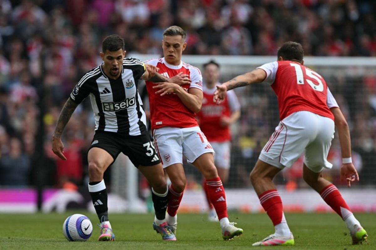 Newcastle United's Brazilian midfielder #39 Bruno Guimaraes (L) vies with Arsenal's Belgian midfielder #19 Leandro Trossard (C) and Arsenal's Polish defender #15 Jakub Kiwior (R) during the English Premier League football match between Arsenal and Newcastle United at the Emirates Stadium in London on May 18, 2025.   Glyn KIRK / AFP