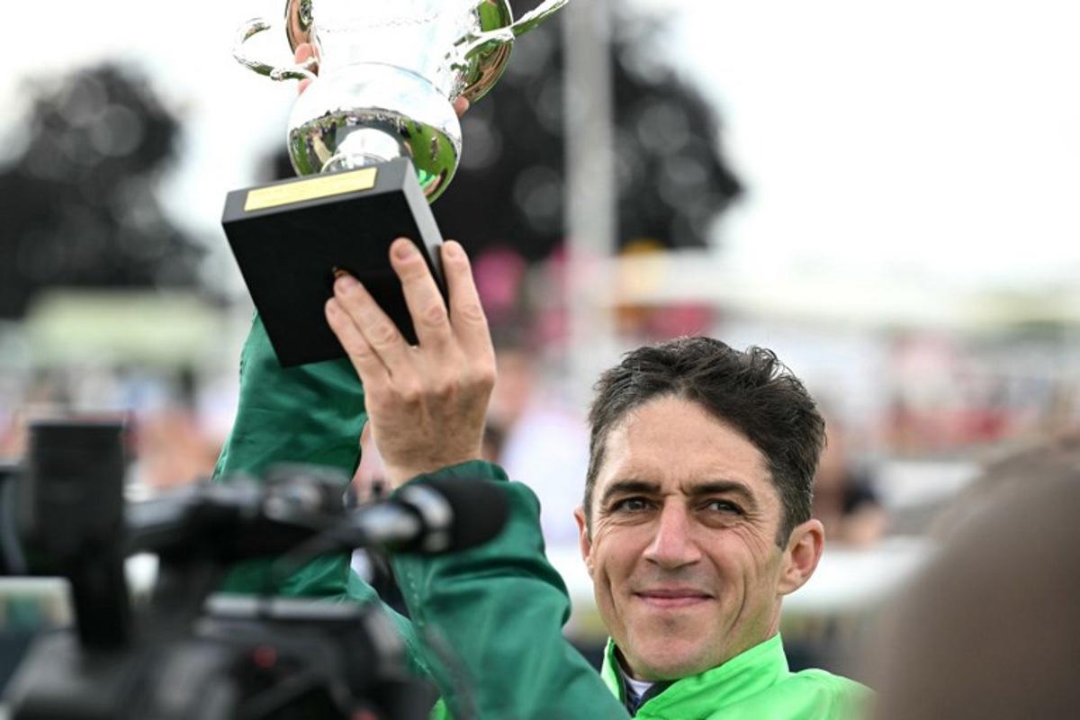Belgium's Christophe Soumillon riding "Gezora" holds the trophy after winning the Diane Longines prize horse race at the Chantilly race course, north of Paris, on June 15, 2025.  Hugo MATHY / AFP