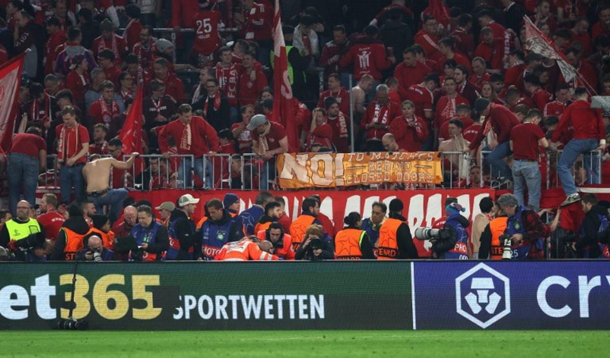 A photographer is treated after fans climbed over the fence after the UEFA Champions League quarter-final second leg football match between FC Bayern Munich and Real Madrid in Munich, southern Germany, on April 15, 2026. Bayern Munich supporters have apologised after several photographers were injured when fans stormed over barriers at the end of Wednesday's home Champions League quarter-final against Real Madrid. Karl-Josef HILDENBRAND / AFP