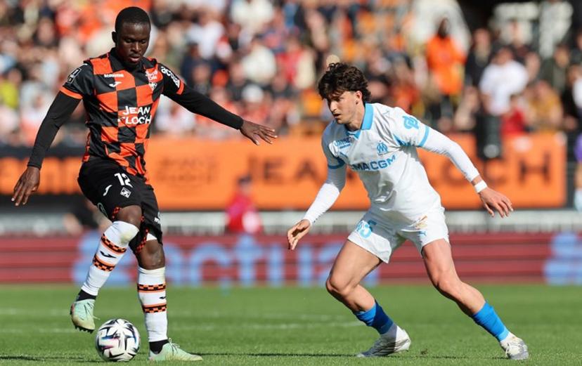 Lorient's Senegalese forward #12 Bamba Dieng (L) fights for the ball with Marseille's Argentinian defender #05 Leonardo Balerdi during the French L1 football match between FC Lorient and Olympique de Marseille at the Moustoir stadium in Lorient, western France on April 18, 2026.  Fred TANNEAU / AFP