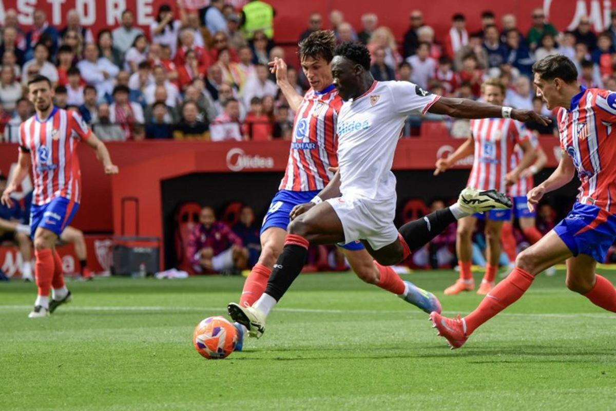 Sevilla's Nigerian forward #15 Akor Adams (C) is challenged by Atletico Madrid's Spanish defender #24 Robin Le Normand (L)during the Spanish league football match between Sevilla FC and Club Atletico de Madrid at the Ramon Sanchez Pizjuan stadium in Seville on April 6, 2025.  CRISTINA QUICLER / AFP