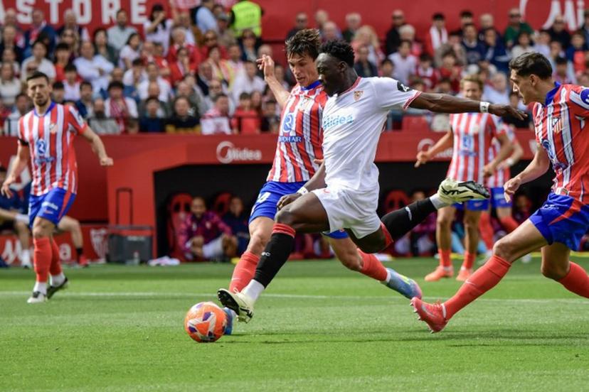 Sevilla's Nigerian forward #15 Akor Adams (C) is challenged by Atletico Madrid's Spanish defender #24 Robin Le Normand (L)during the Spanish league football match between Sevilla FC and Club Atletico de Madrid at the Ramon Sanchez Pizjuan stadium in Seville on April 6, 2025.  CRISTINA QUICLER / AFP
