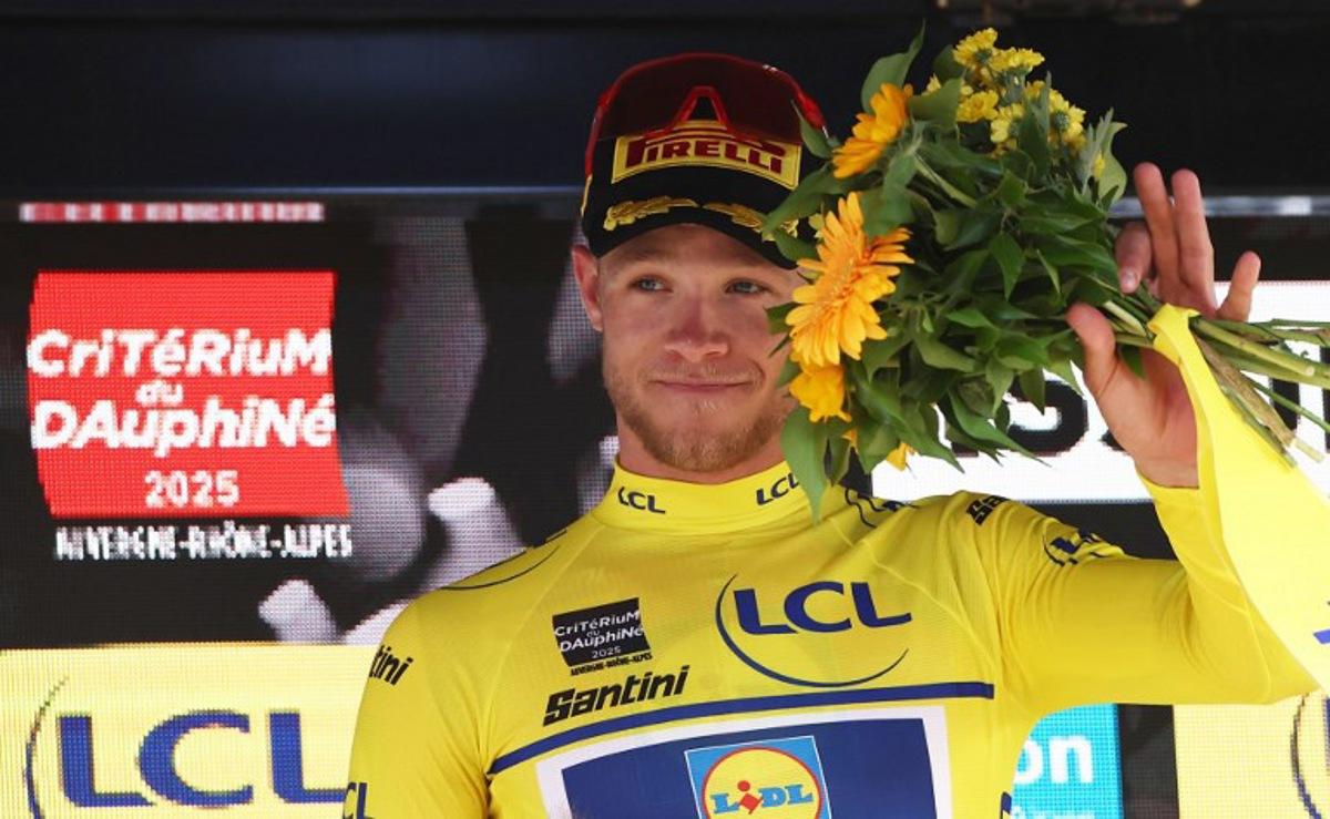Lidl-Trek's Italian rider Jonathan Milan wearing the overall leader's yellow jersey celebrates on the podium of the 2nd stage of the 77th edition of the Criterium du Dauphine cycling race, 204,6 km between Prémilhat and Issoire, on June 9, 2025.  Anne-Christine POUJOULAT / AFP