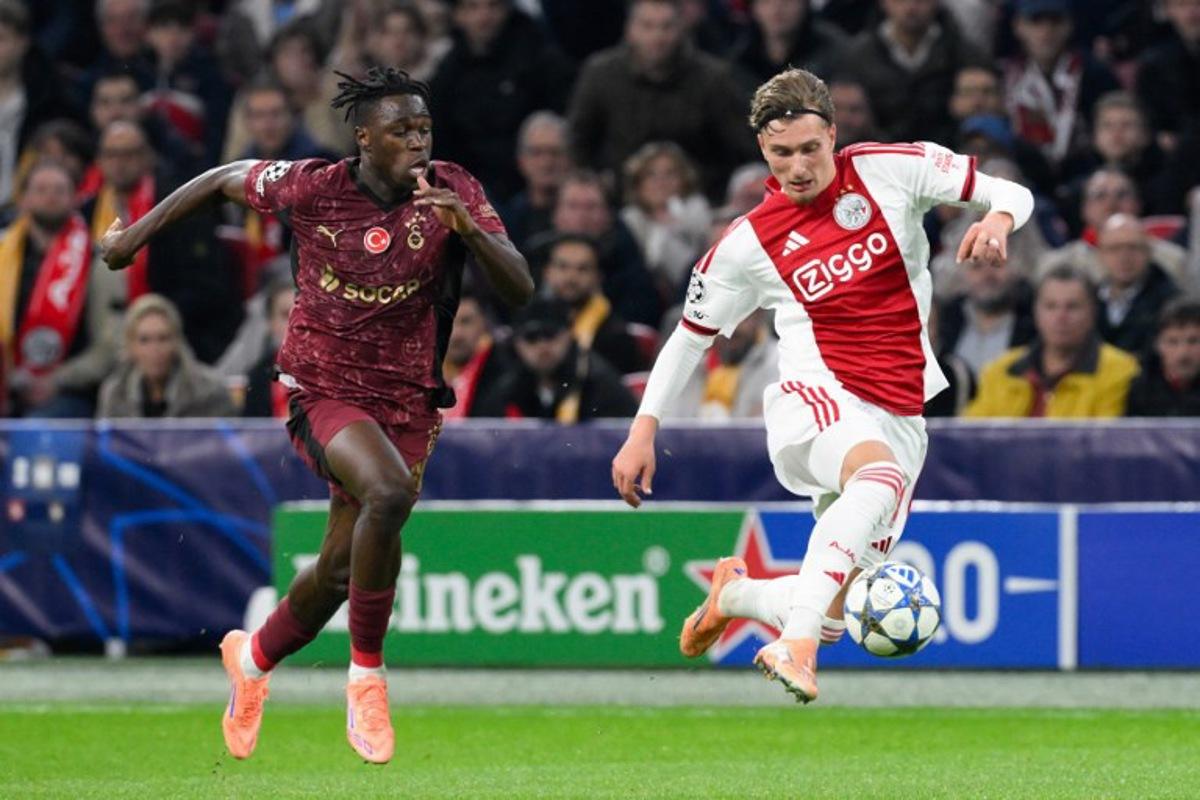 Ajax's Belgian forward #11 Mika Godts (R) fights for the ball with Galatasaray's Ivorian defender #90 Wilfried Singo (L) during the UEFA Champions League, league phase day 4, football match between Ajax and Galatasaray at the Johan Cruijff ArenA in Amsterdam on November 5, 2025.  JOHN THYS / AFP