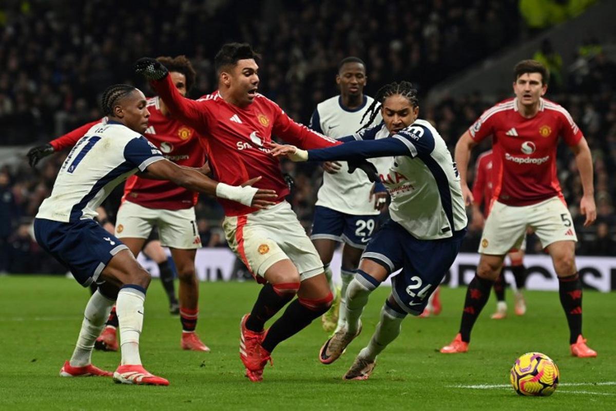 Manchester United's Brazilian midfielder #18 Casemiro (C) falls under a challenge from Tottenham Hotspur's French striker #11 Mathys Tel (L) and Tottenham Hotspur's English defender #24 Djed Spence (2R) but no penalty is given, during the English Premier League football match between Tottenham Hotspur and Manchester United at the Tottenham Hotspur Stadium in London, on February 16, 2025.  Glyn KIRK / AFP