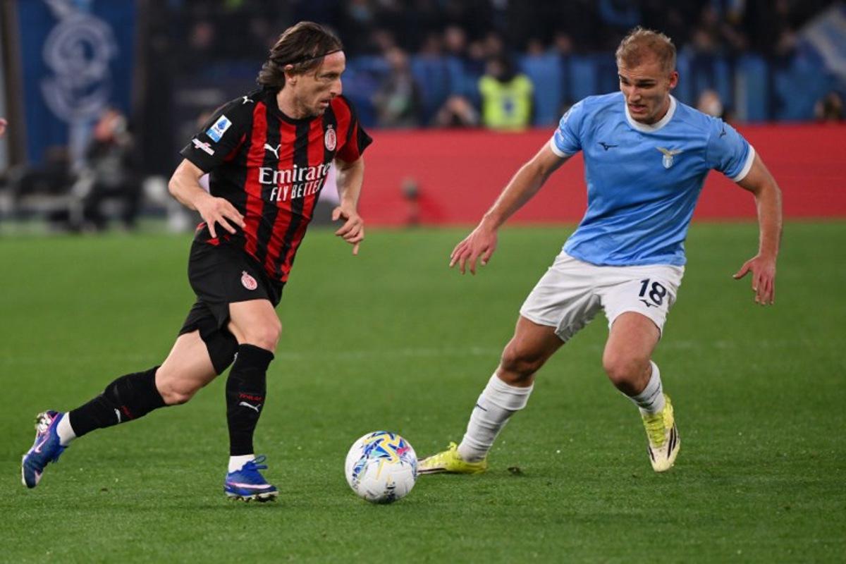 AC Milan's Croatian midfielder #14 Luka Modric runs with the ball in front of Lazio's Danish forward #18 Gustav Isaksen (R) during the Italian Serie A football match between Lazio and AC Milan at the Olympic Stadium in Rome on March 15, 2026.  Alberto PIZZOLI / AFP