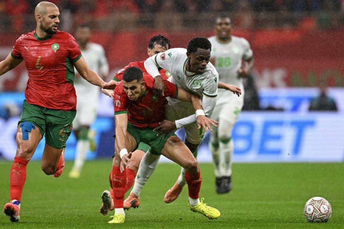 Morocco's midfielder #04 Sofyan Amrabat, Morocco's defender #18 Jawad El Yamiq and Comoros's forward #11 Rafiki Said vie during the Africa Cup of Nations (CAN) group A  football match between Morocco and Comoros at Prince Moulay Abdellah Stadium in Rabat on December 21, 2025.   Paul ELLIS / AFP