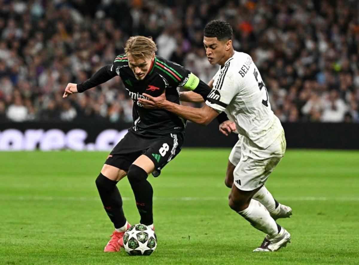 Real Madrid's English midfielder #05 Jude Bellingham fights for the ball with Arsenal's Norwegian midfielder #08 Martin Odegaard during the UEFA Champions League quarter final second leg football match between Real Madrid CF and Arsenal at Santiago Bernabeu Stadium in Madrid on April 16, 2025.  JAVIER SORIANO / AFP