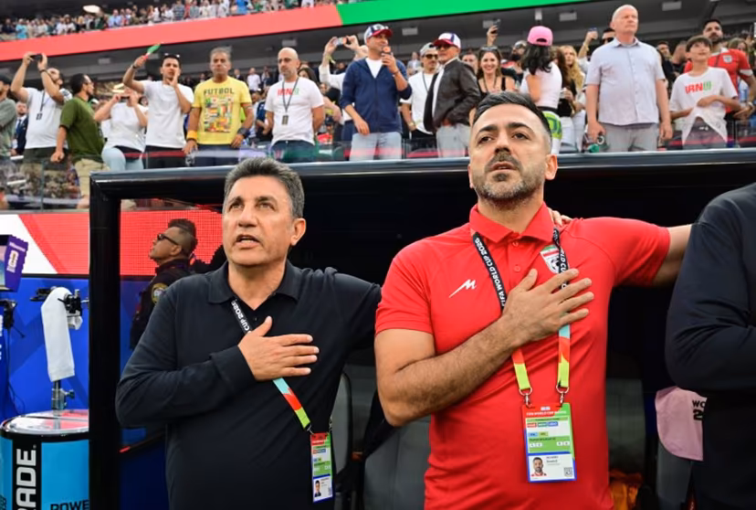 Iran's head coach Amir Ghalenoei (L) and assistant coach Saeed Alhoei (R) sing the national anthem ahead of the 2026 World Cup Group G football match between Iran and New Zealand at Los Angeles Stadium in Inglewood on June 15, 2026. Frederic J. Brown / AFP