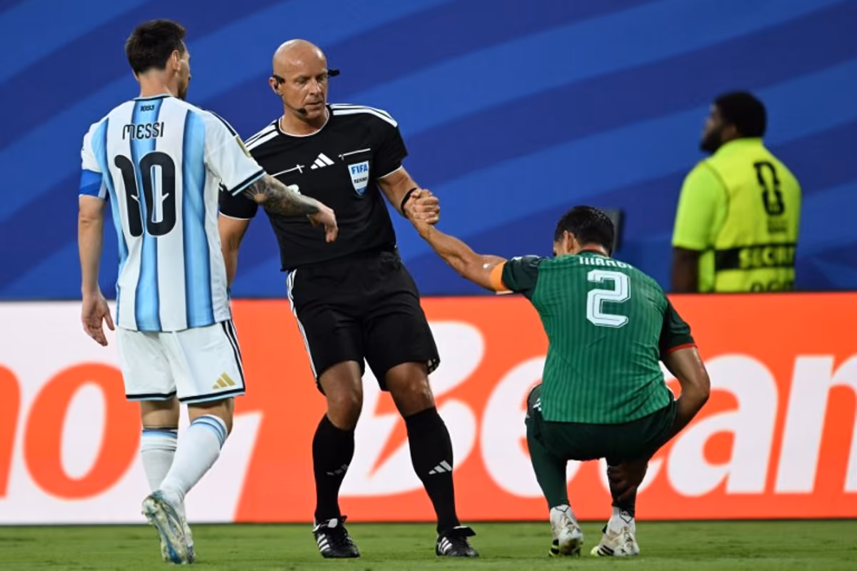 Polish referee Szymon Marciniak lifts Algeria's defender #02 Aissa Mandi as he reacts in pain next to Argentina's forward #10 Lionel Messi during the 2026 World Cup Group J football match between Argentina and Algeria at the Kansas City Stadium in Kansas City on June 16, 2026. ROBERTO SCHMIDT / AFP