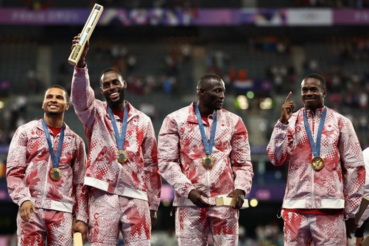 Gold medallists Canada's Andre De Grasse, Brendon Rodney, Jerome Blake and Aaron Brown celebrate on the podium after competing in the men's 4x100m relay final of the athletics event during the Paris 2024 Olympic Games at Stade de France in Saint-Denis, north of Paris, on August 9, 2024. Anne-Christine POUJOULAT / AFP